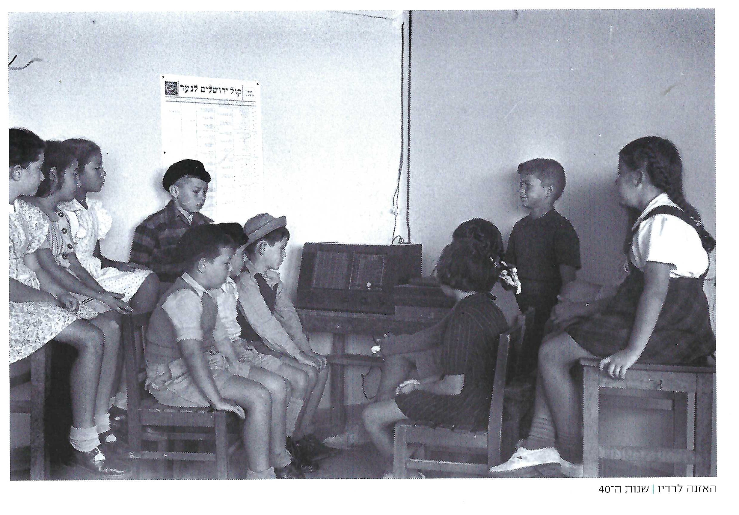 Photo by Daniel Kaplan, Kfar Sava, shows group of children at Ussishkin  School sitting by radio with wall chart, November 1946